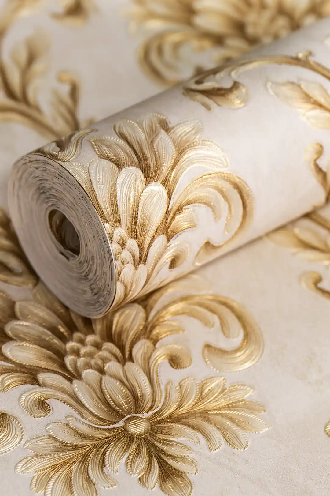 Rolled gold baroque damask wallpaper showing embossed floral scrollwork pattern on cream background