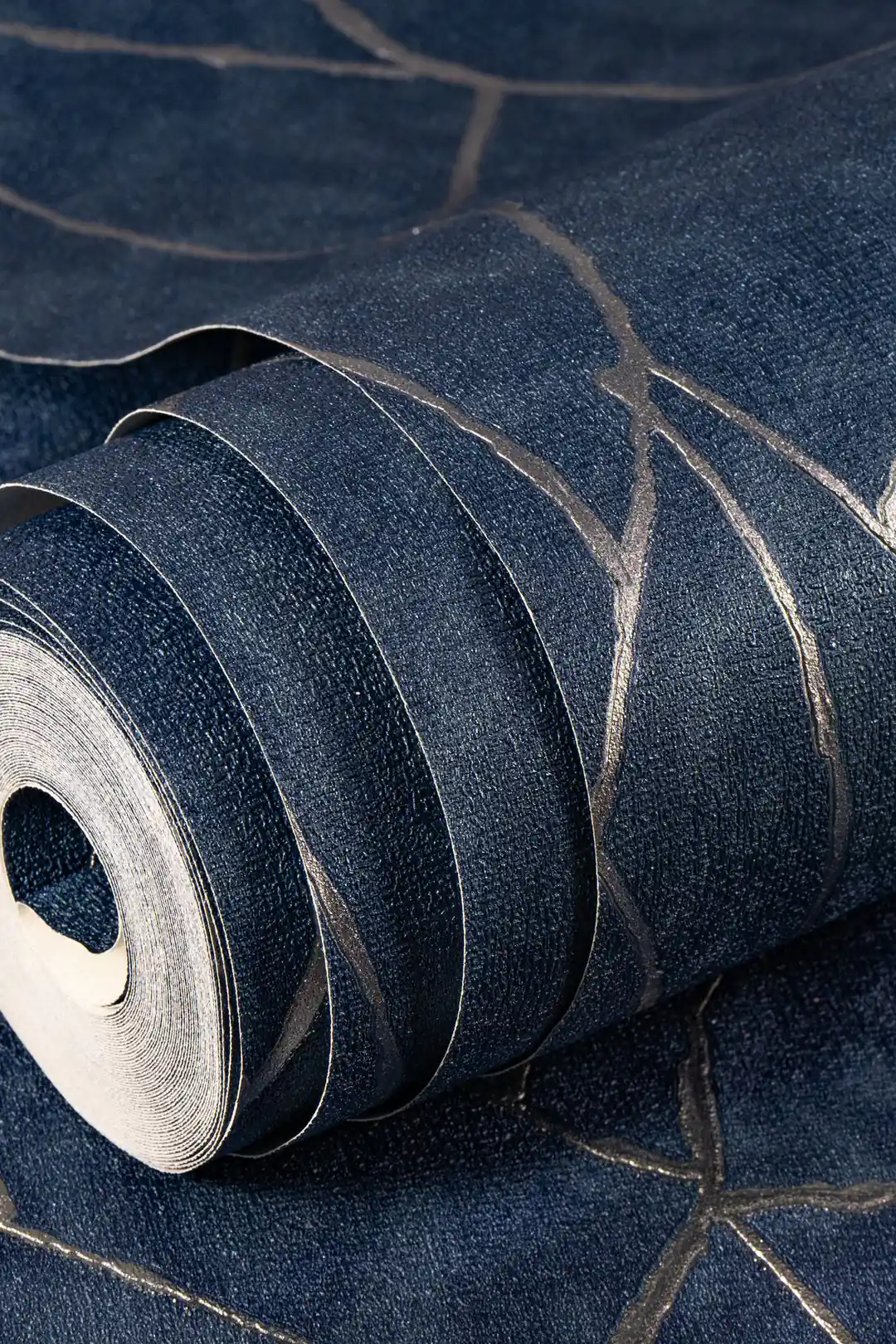 Room scene with navy abstract wallpaper installed behind mauve sofa, copper pendant lamp, and tropical green plant