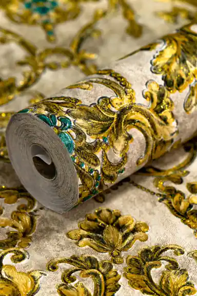 Rolled wallpaper showing ornate gold damask pattern with turquoise gem details on aged cream background