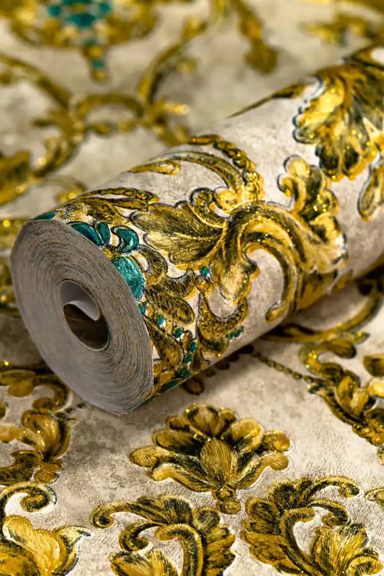 Rolled wallpaper showing ornate gold damask pattern with turquoise gem details on aged cream background