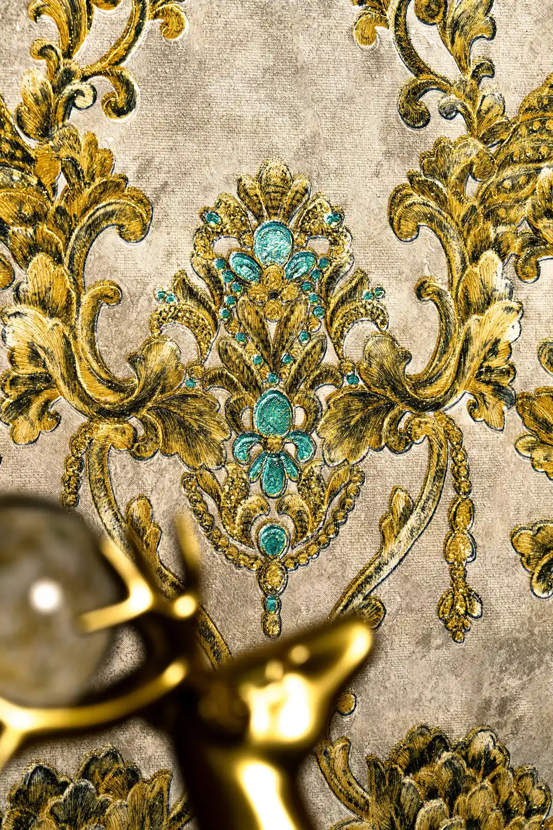 Close-up of ornate gold damask medallion with turquoise jewel centre and scrolling acanthus leaves