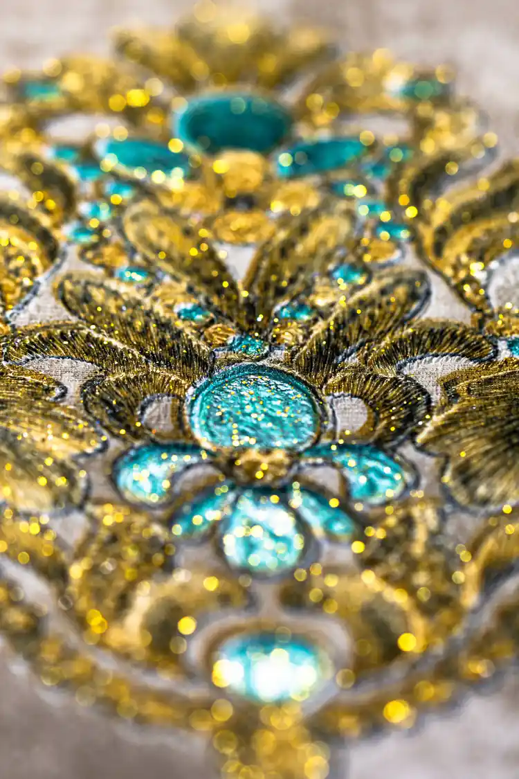 Macro shot of sparkling turquoise gem and gold glitter detailing on baroque wallpaper motif