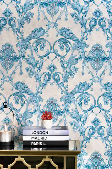 Installed teal damask wallpaper with ornate pattern behind stacked travel books and red succulent plant