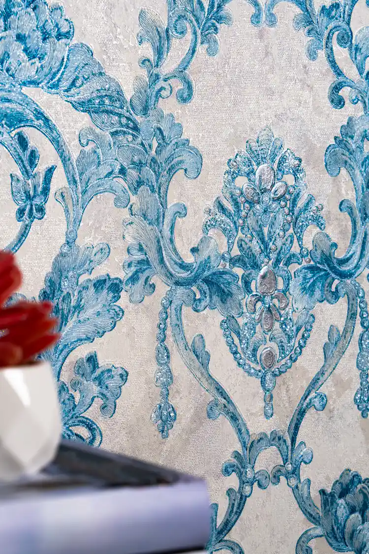 Close-up of teal baroque scrollwork and jeweled medallion motif with subtle glitter texture on wallpaper