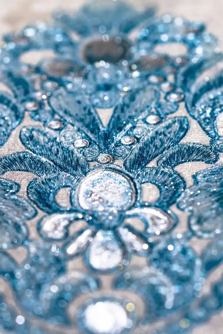 Extreme macro of sparkling teal blue glitter crystals and embossed floral detail on wallpaper surface