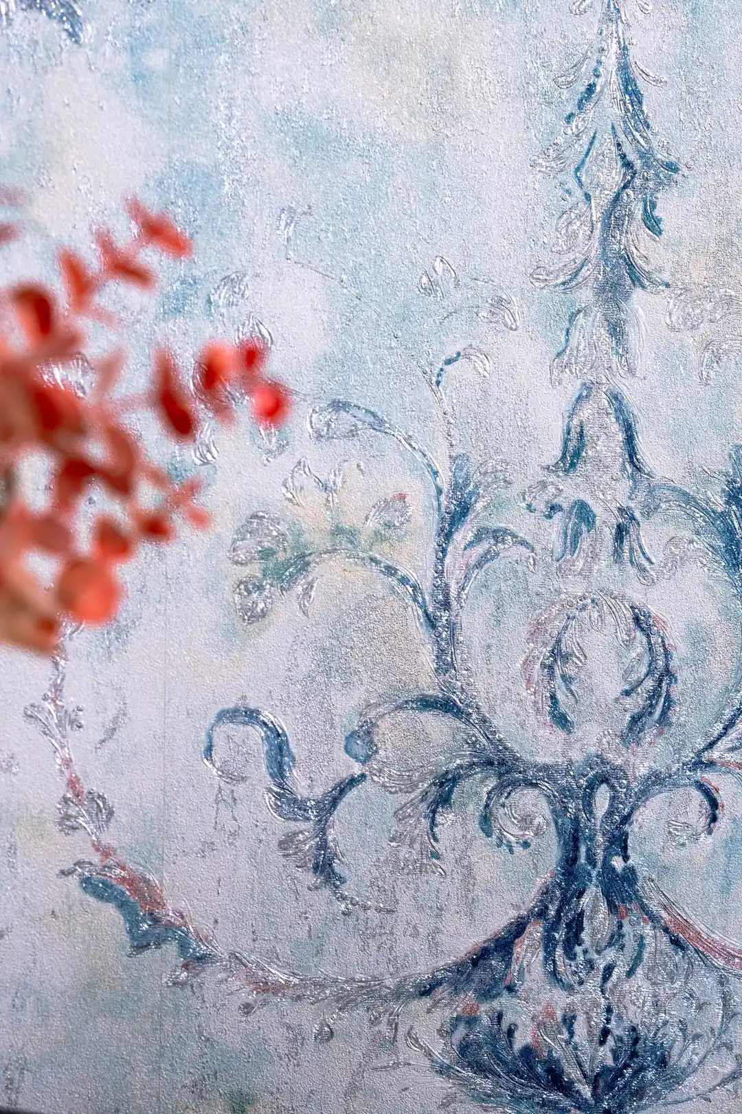 Close-up of blue vintage damask motif with coral dried flowers blurred in foreground