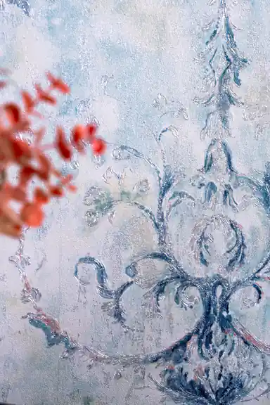 Close-up of blue vintage damask motif with coral dried flowers blurred in foreground