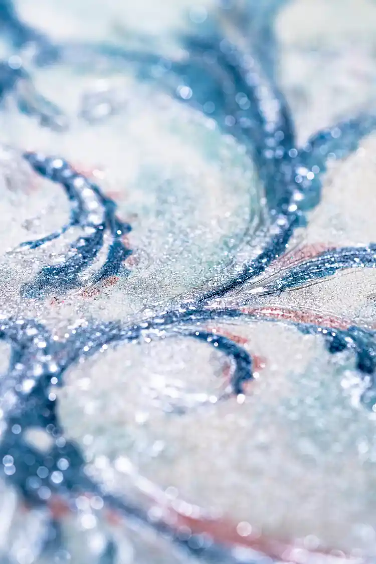 Macro detail of shimmering blue and pink glitter texture on vintage damask wallpaper scrollwork