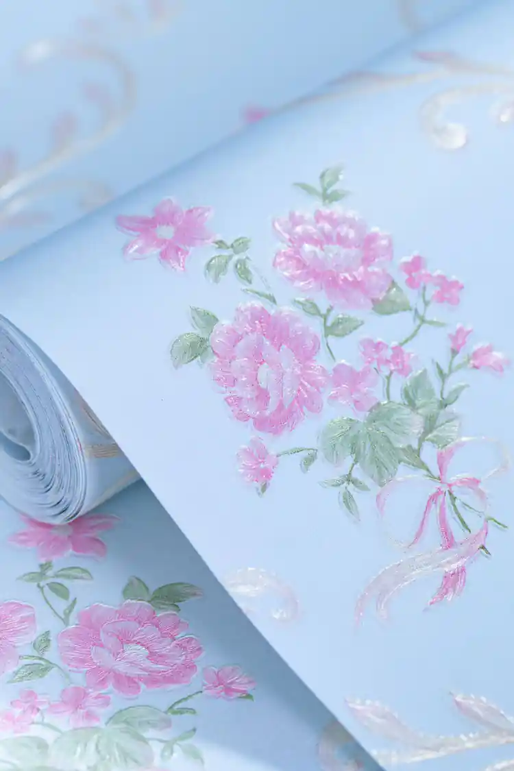 Flat-lay of unrolled wallpaper roll showing pink rose bouquets on light blue background with gold scrolls