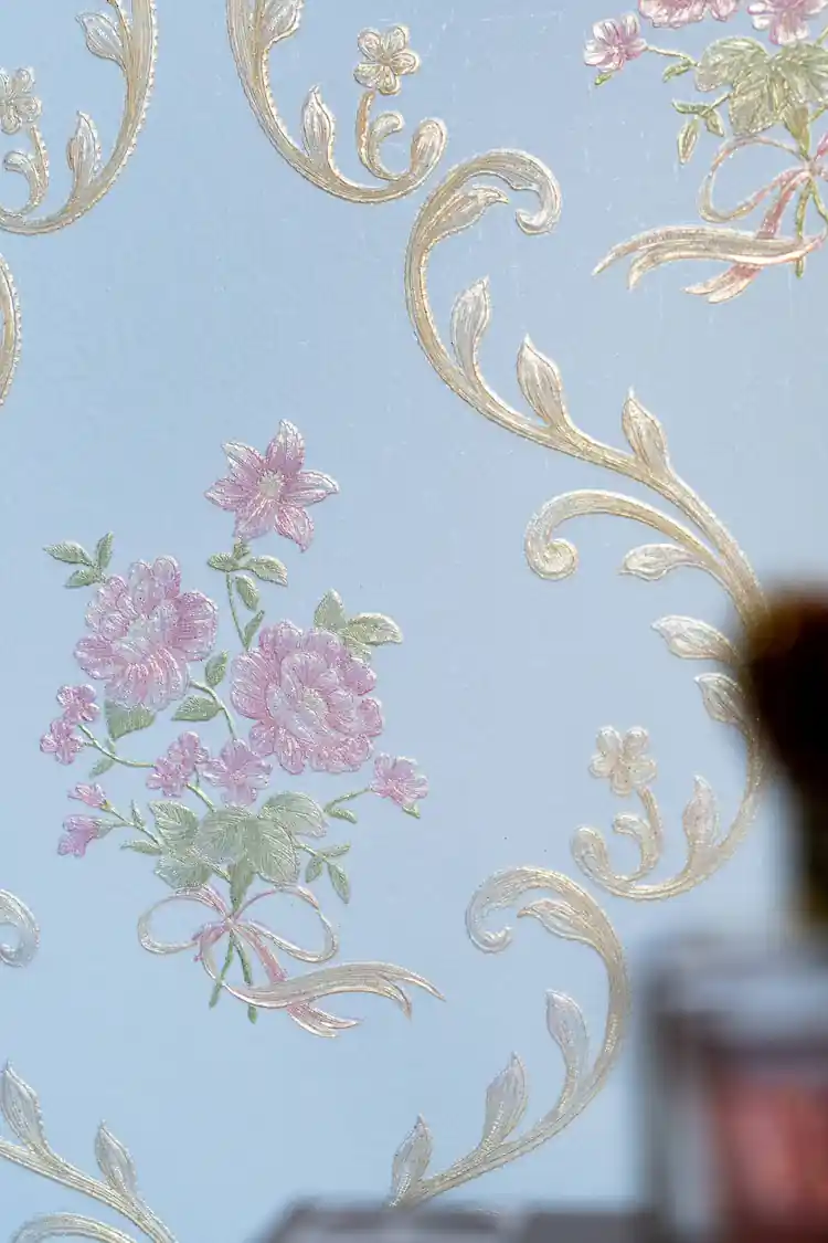 Close-up of embossed pink rose cluster and gold acanthus scroll on powder blue wallpaper background