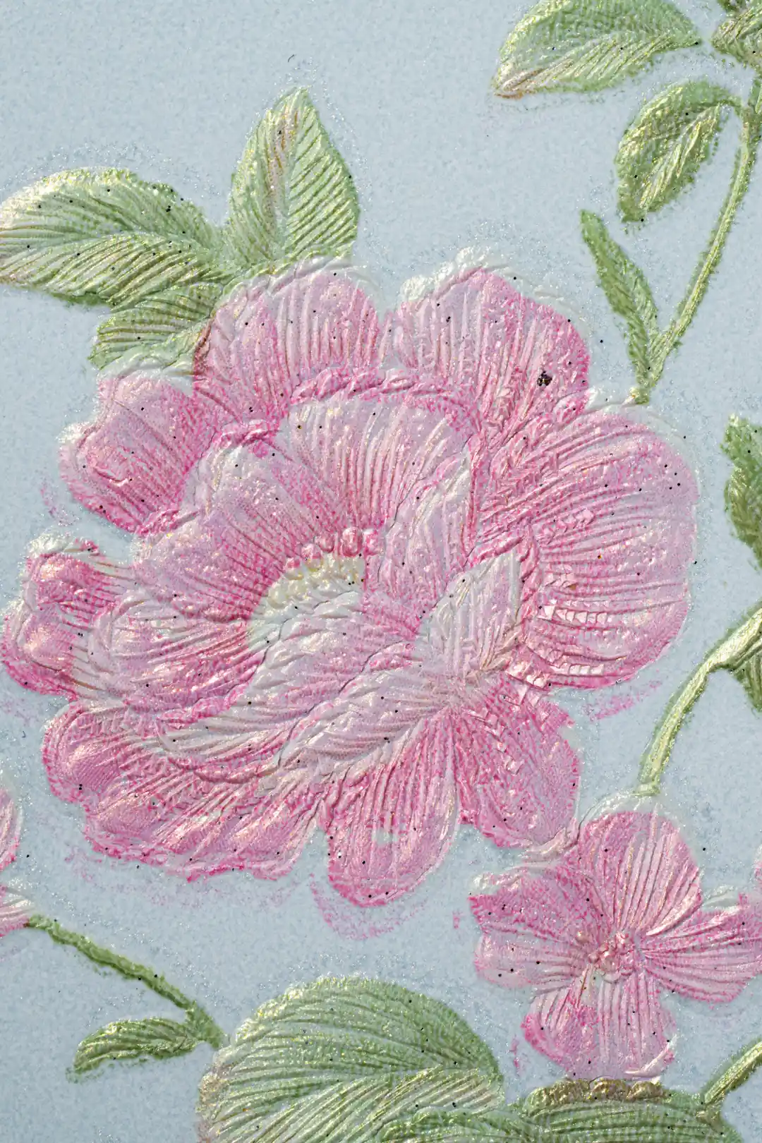 Extreme close-up of deeply embossed pink peony bloom with green leaf detail on blue wallpaper surface