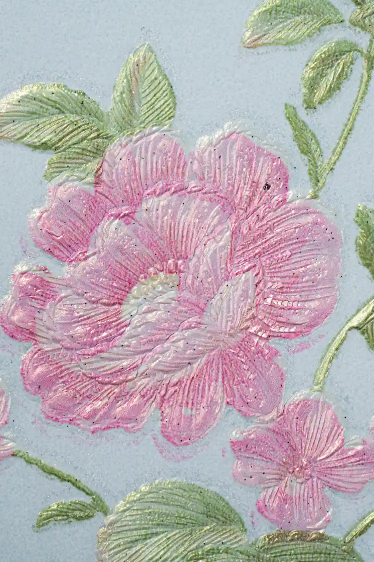 Extreme close-up of deeply embossed pink peony bloom with green leaf detail on blue wallpaper surface