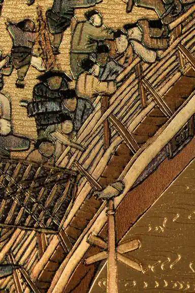 Extreme close-up of embossed golden metallic texture showing people crossing bridge in ancient village scene