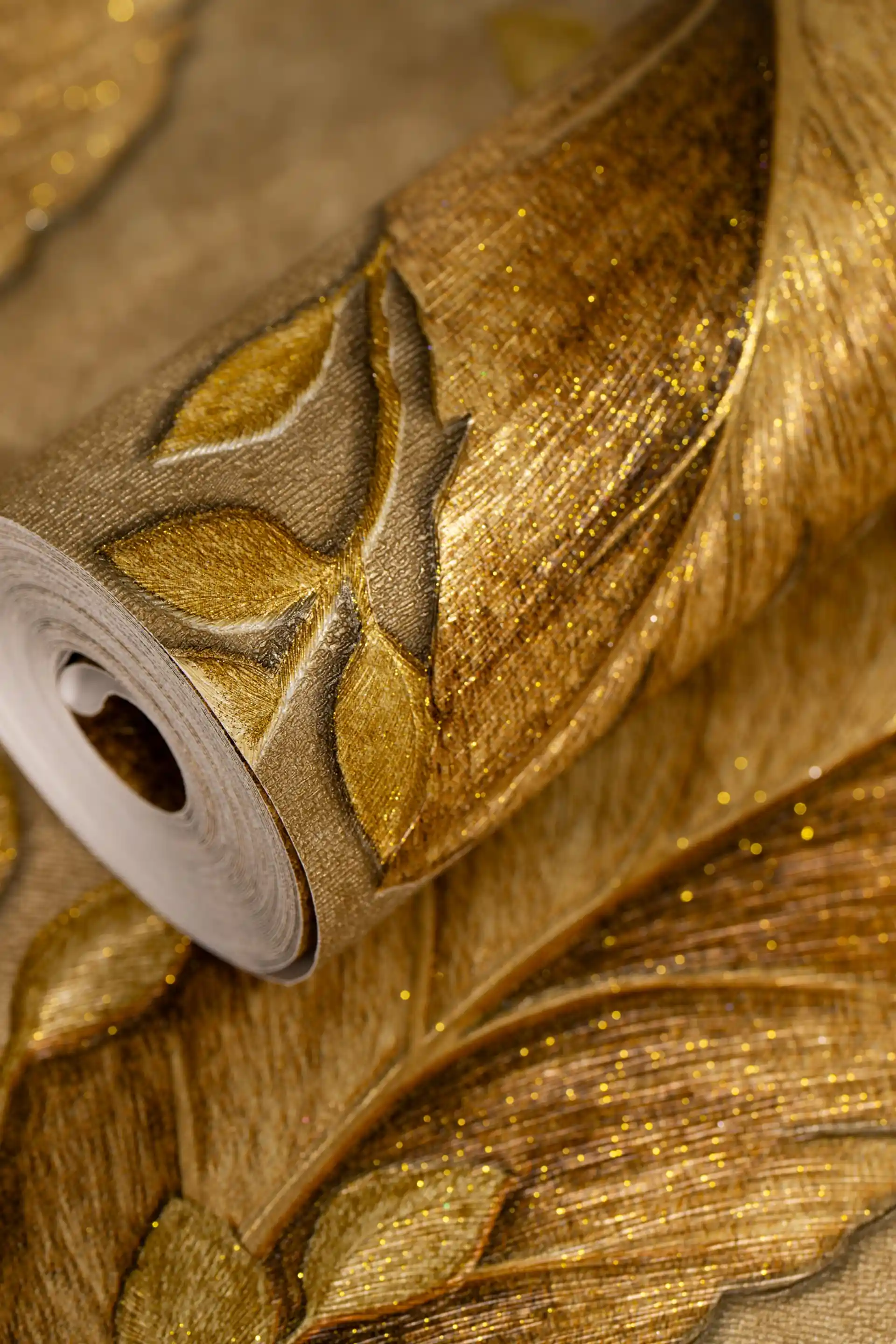 Rolled tropical golden leaves wallpaper showing large embossed leaf pattern with glitter on warm background