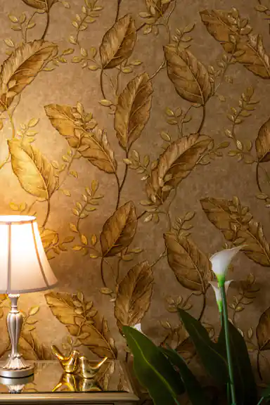 Installed golden leaf wallpaper showing full repeat pattern with lamp and decorative accessories