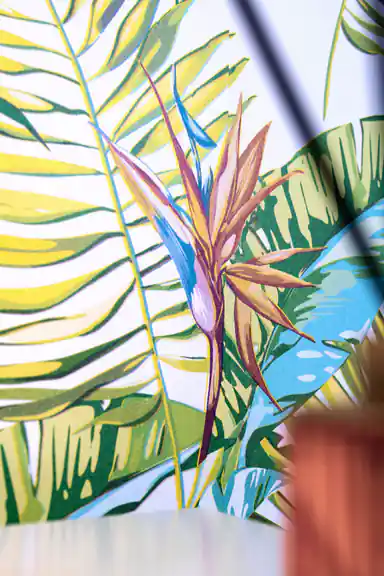 Close-up of bird of paradise flower and green palm leaf detail on tropical wallpaper