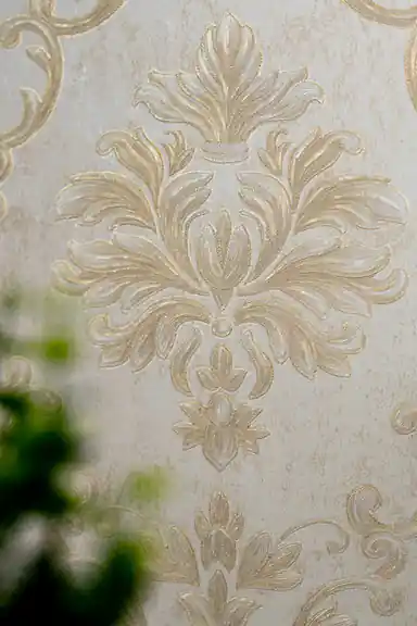 Extreme macro of deeply embossed gold acanthus leaf texture showing fine ridges on cream wallpaper