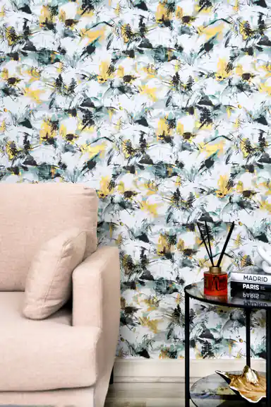 Living room with abstract ink-splash wallpaper in teal, black, and gold behind a pink armchair and side table