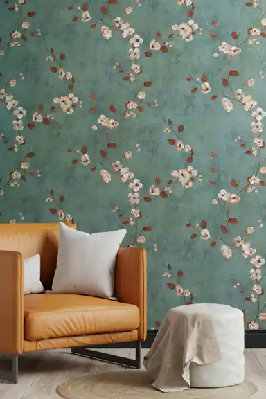 Living room with teal blossom branch wallpaper behind a tan leather armchair with white cushion and a woven pouf