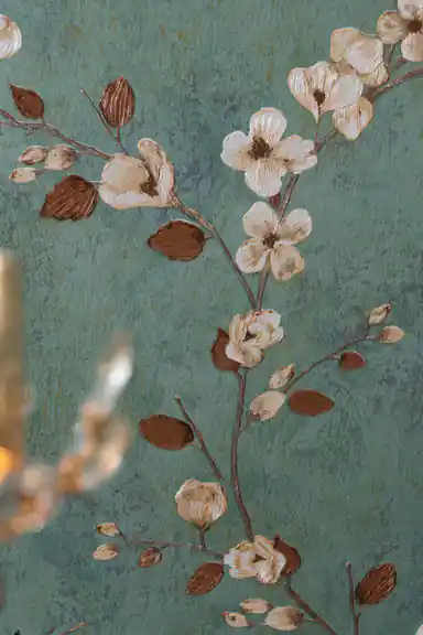 Close-up of white magnolia bloom and brown bud on dark teal branch against green wallpaper background