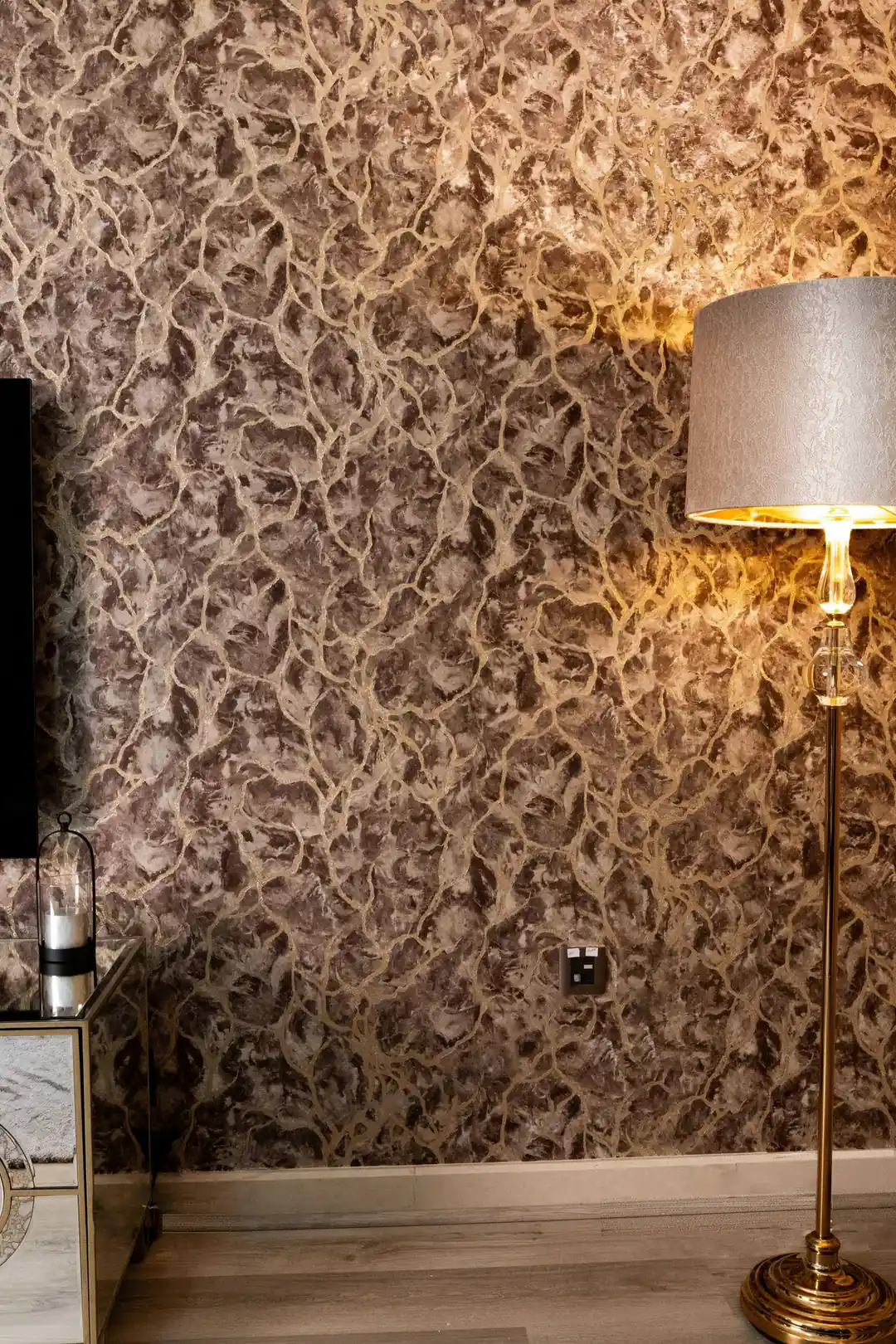 Installed brown marble wallpaper with golden veins in a living room with floor lamp and warm lighting