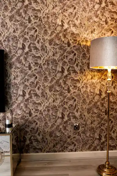 Installed brown marble wallpaper with golden veins in a living room with floor lamp and warm lighting