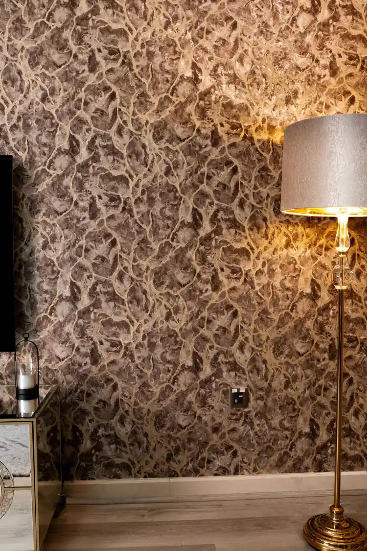 Installed brown marble wallpaper with golden veins in a living room with floor lamp and warm lighting