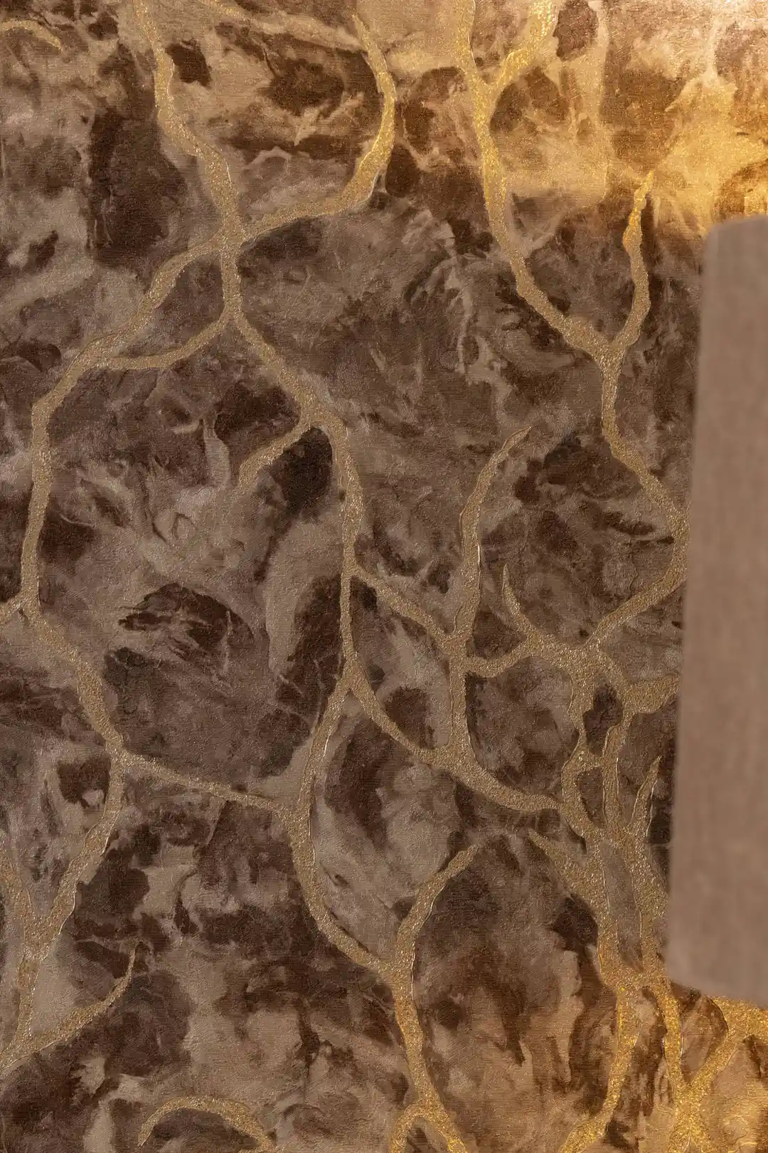 Close-up of brown marble wallpaper showing gold glitter veins and aged stone texture detail