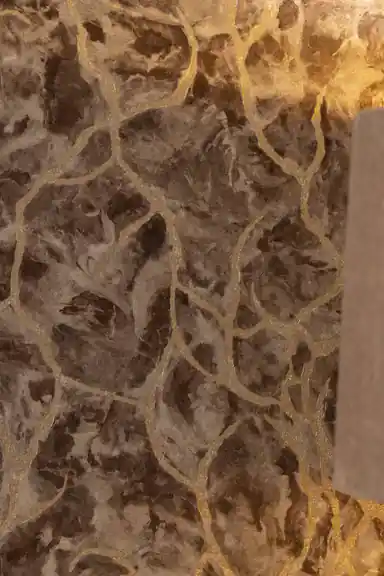 Close-up of brown marble wallpaper showing gold glitter veins and aged stone texture detail