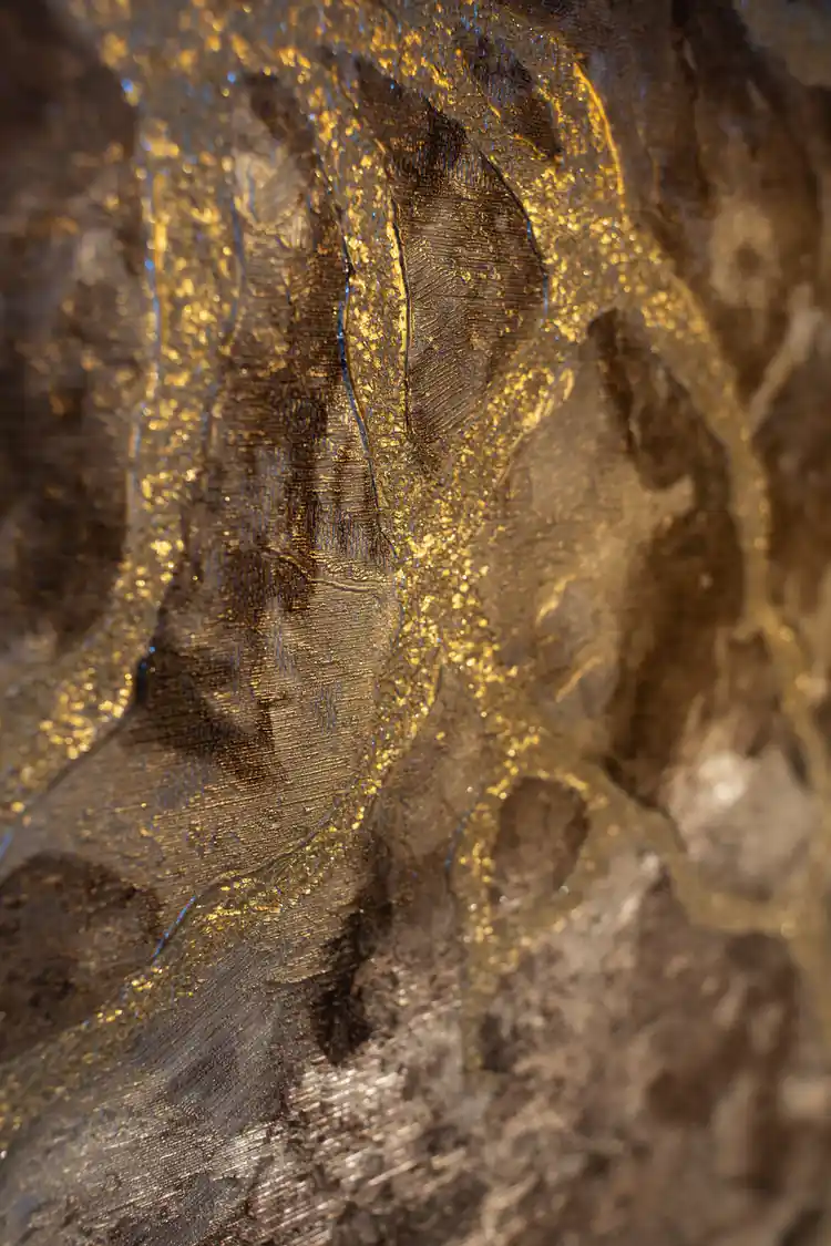 Extreme macro of antiqued brown marble wallpaper revealing gold metallic scroll texture