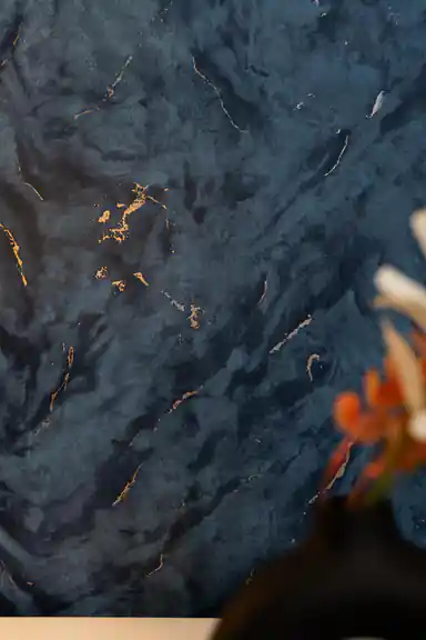 Close-up of midnight blue marble wallpaper revealing gold and silver veins on smooth surface