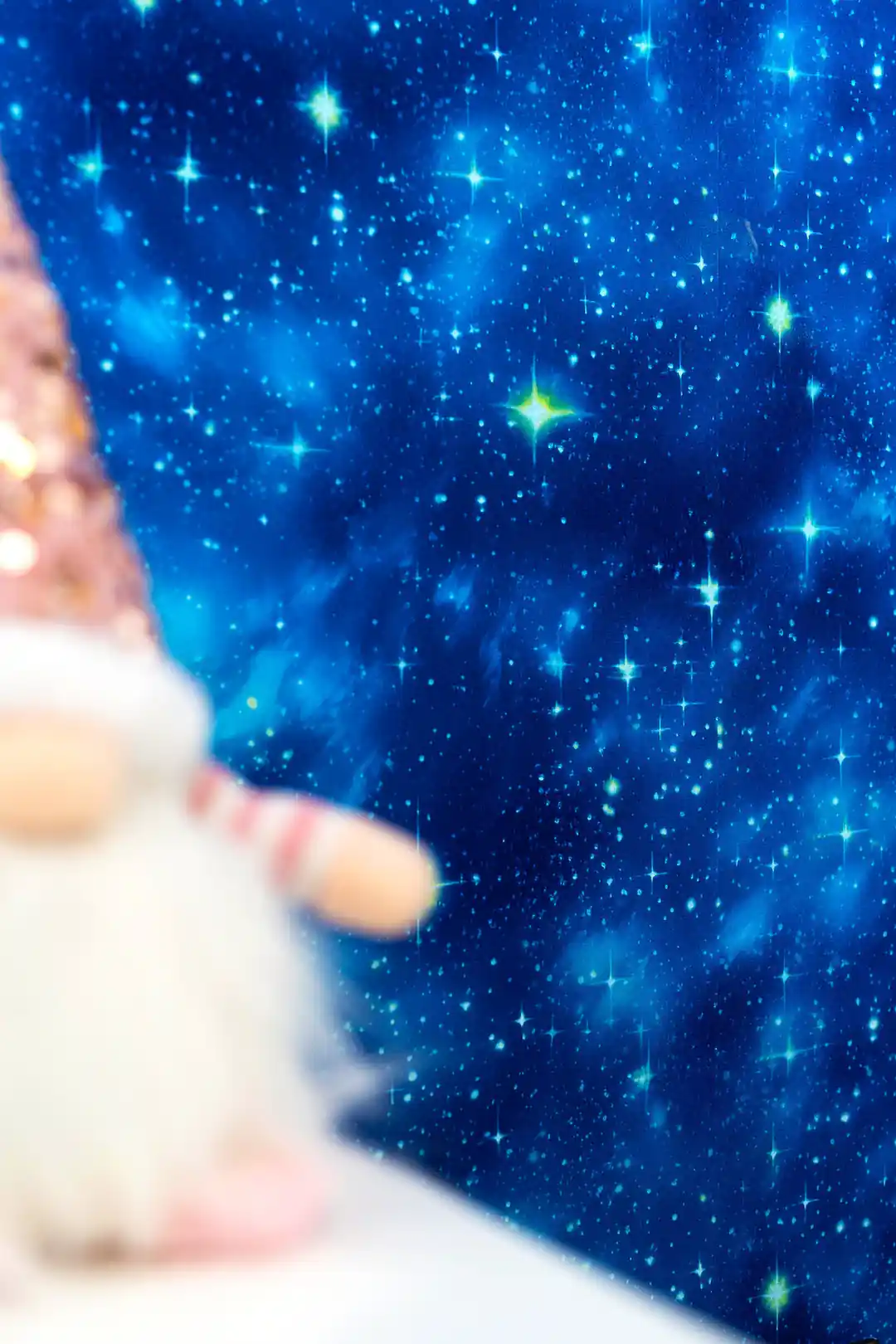 Close-up of starry blue galaxy wallpaper with bright glowing star effects and a decorative figurine in the foreground