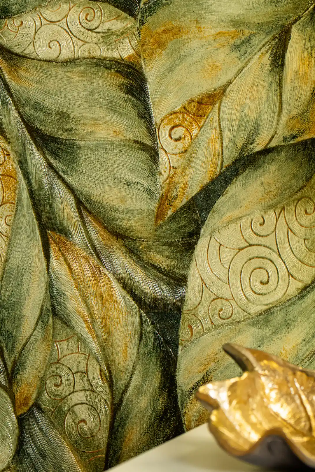 Embossed green and gold swirl leaf pattern wallpaper installed on wall with teal base and floral motifs