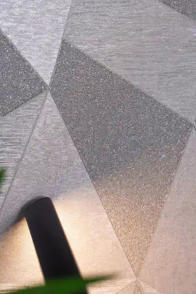 Close-up of grey 3D geometric triangle facets with silver sparkle glitter texture on wallpaper surface