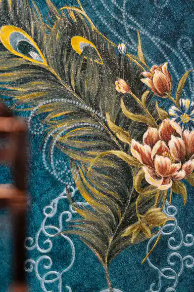 Close-up of embossed peacock feather with tulip flowers and glitter highlights on teal background