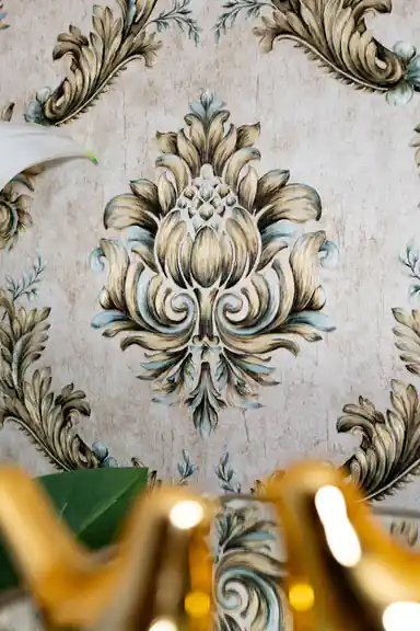 Close-up of single gold and teal baroque damask motif with detailed embossed floral scrollwork
