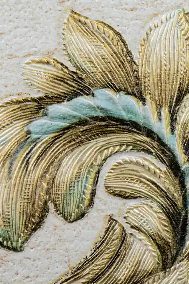 Extreme macro of embossed gold and teal acanthus leaf showing raised texture and fine striations