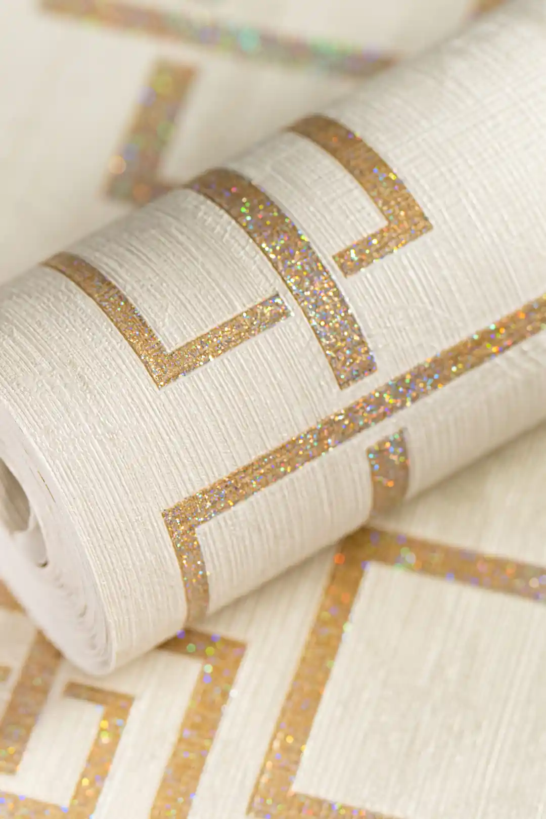 Golden glittery maze wallpaper roll with interlocking square pattern and holographic shimmer finish