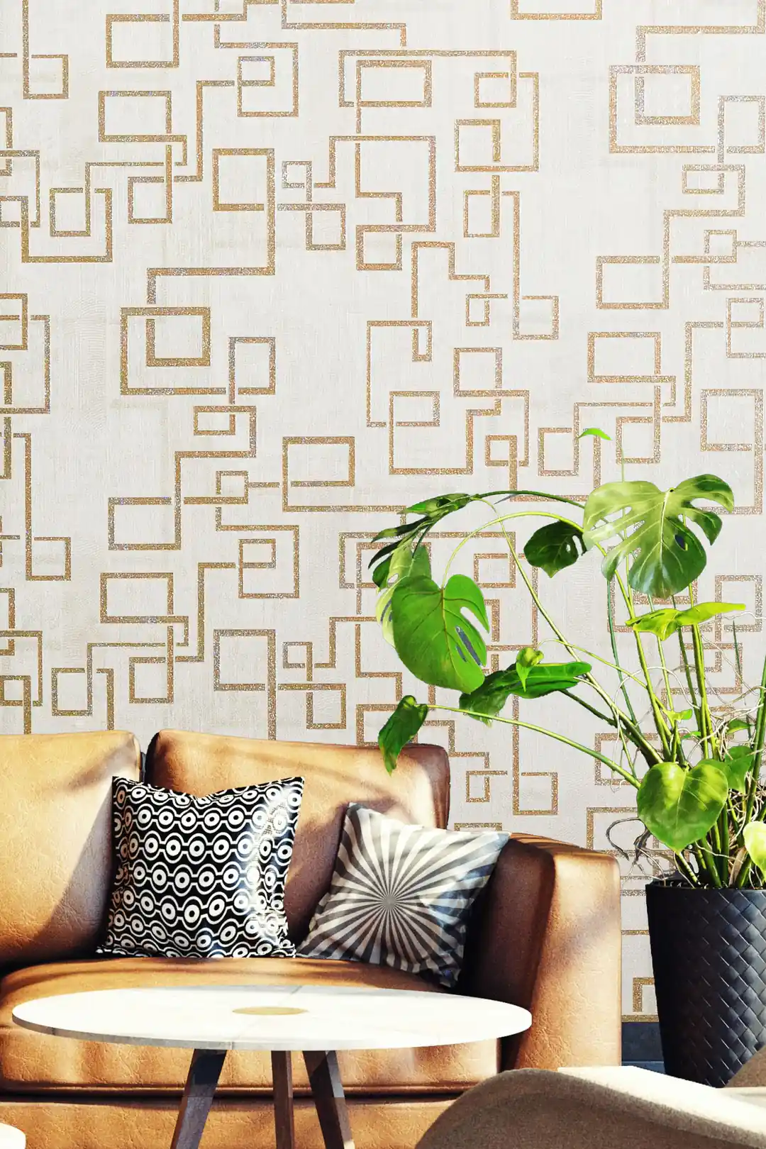 Gold maze pattern wallpaper in living room with tan leather sofa, monstera plant and round table