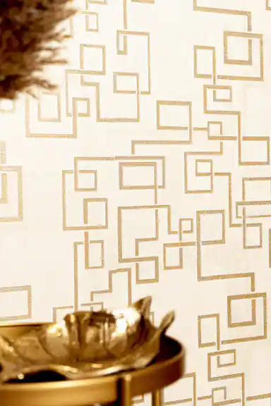Interlocking gold squares wallpaper behind gold decorative bowl and dried flowers arrangement