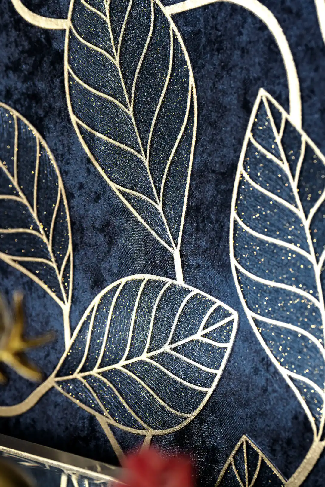 Close-up of midnight blue wallpaper with embossed gold leaf outline pattern and glitter accents