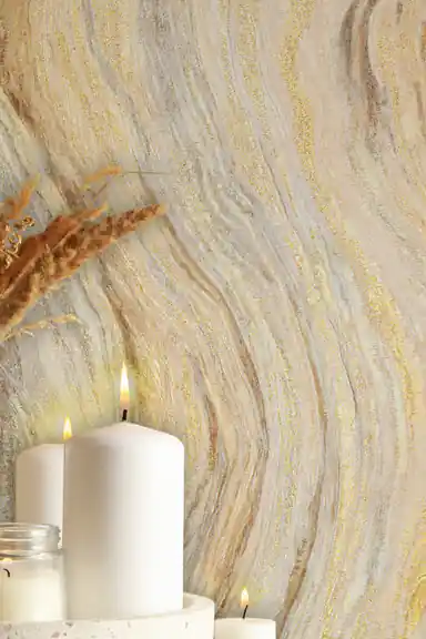 Marble wave wallpaper with gold glitter veins behind white candles and dried wheat decoration