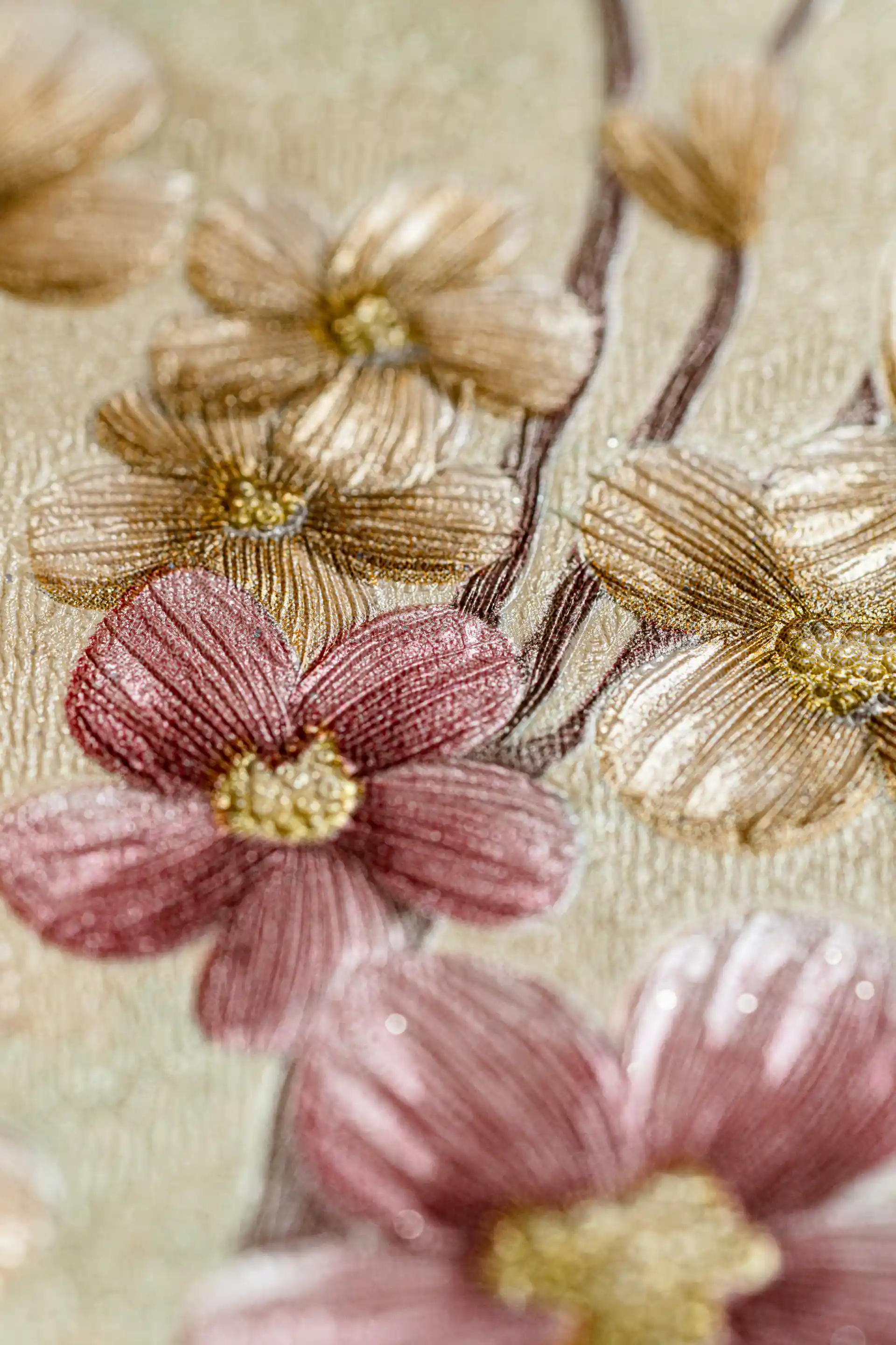 Close-up of embossed floral blooming branches wallpaper with pink and gold flowers on golden base