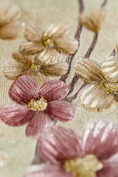 Close-up of embossed floral blooming branches wallpaper with pink and gold flowers on golden base
