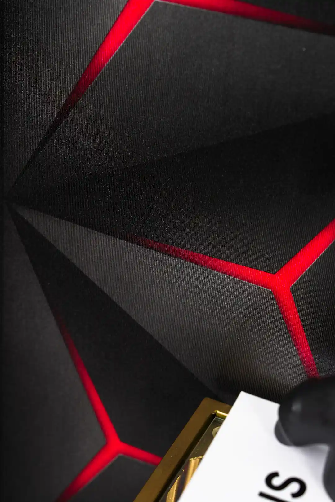 Close-up of installed black hexagonal wallpaper with vivid red illuminated edges and geometric depth