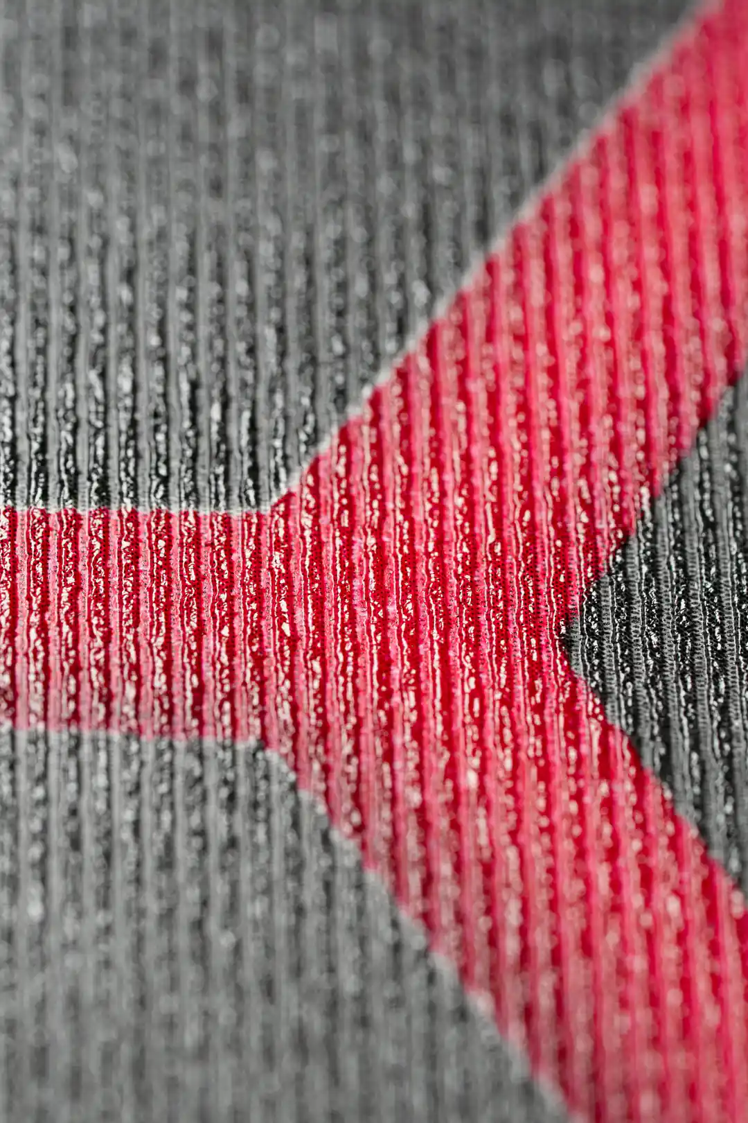 Extreme close-up of the ribbed wallpaper texture showing dark charcoal surface with red accent lines