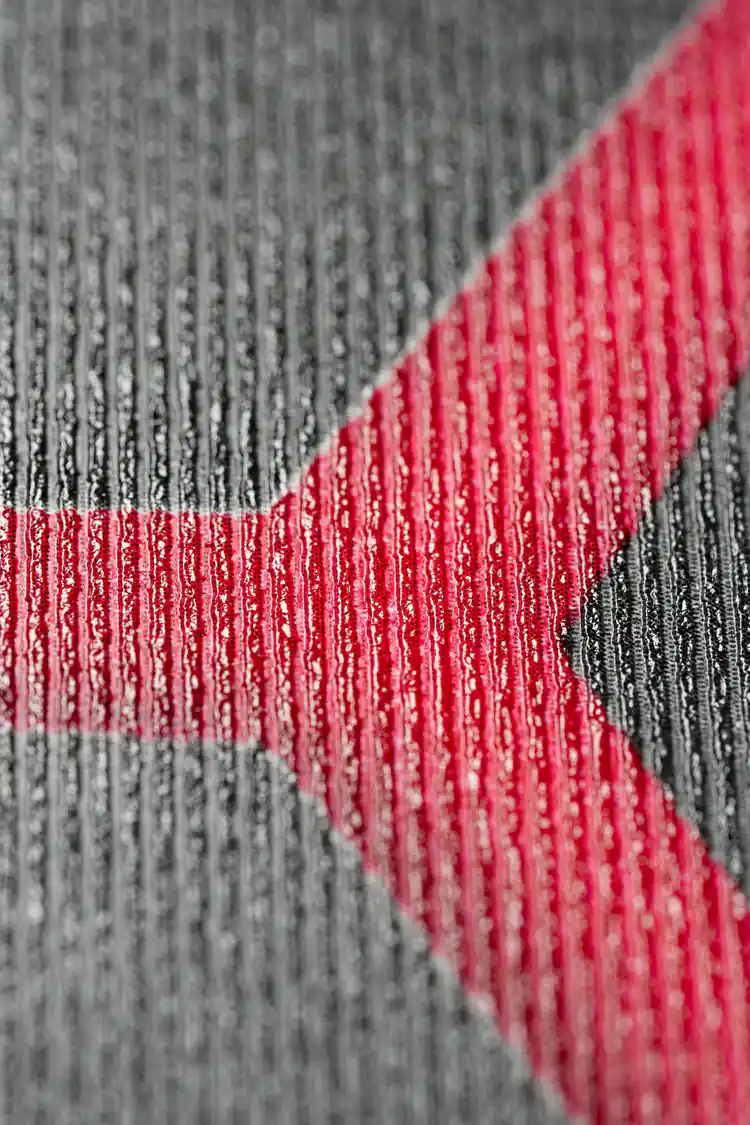 Extreme close-up of the ribbed wallpaper texture showing dark charcoal surface with red accent lines
