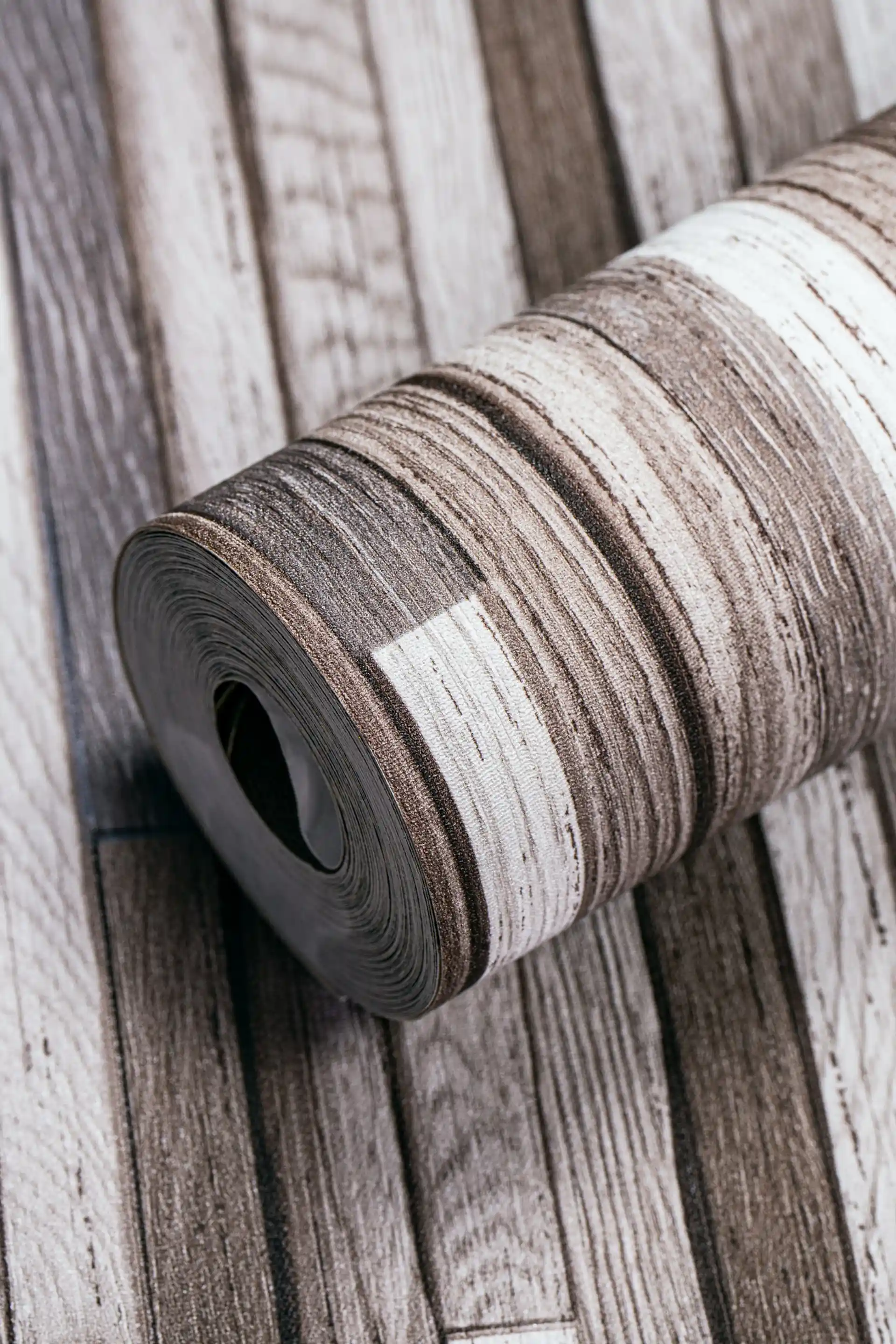 Weathered multicolor wood plank wallpaper roll showing rustic brown, grey, and white distressed plank pattern