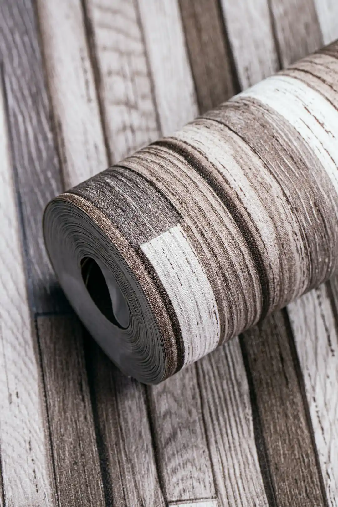 Weathered multicolor wood plank wallpaper roll showing rustic brown, grey, and white distressed plank pattern