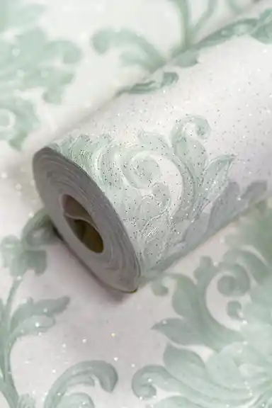 Sage green damask wallpaper roll with embossed floral scroll pattern and sparkling glitter accents